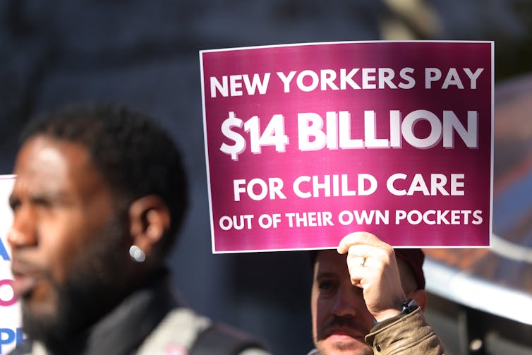 People hold signs at a news conference.
