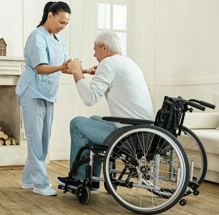 Une femme aidant un homme en fauteuil roulant