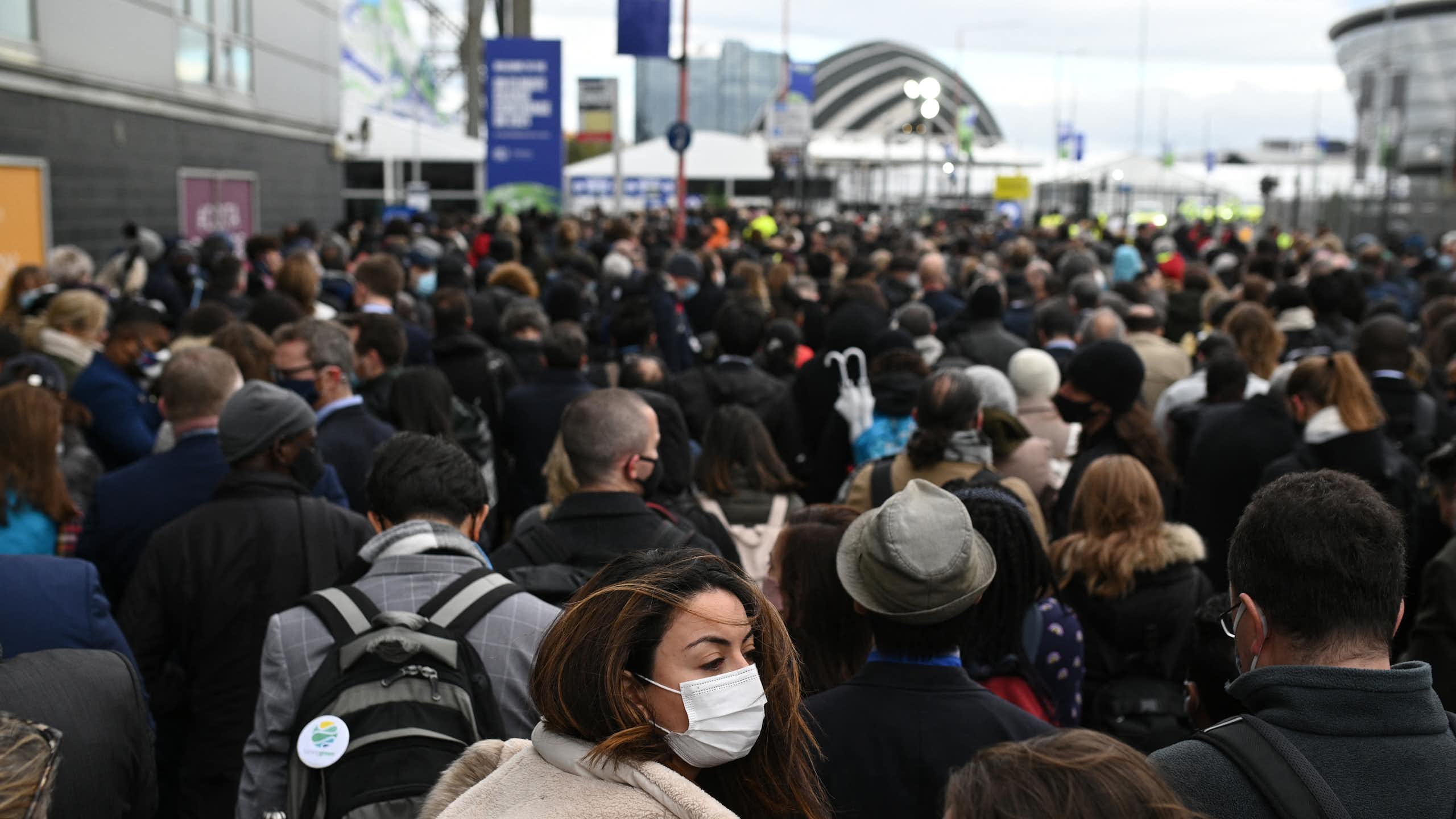 A crowd of people is seen in front of a building or event space in the distance.