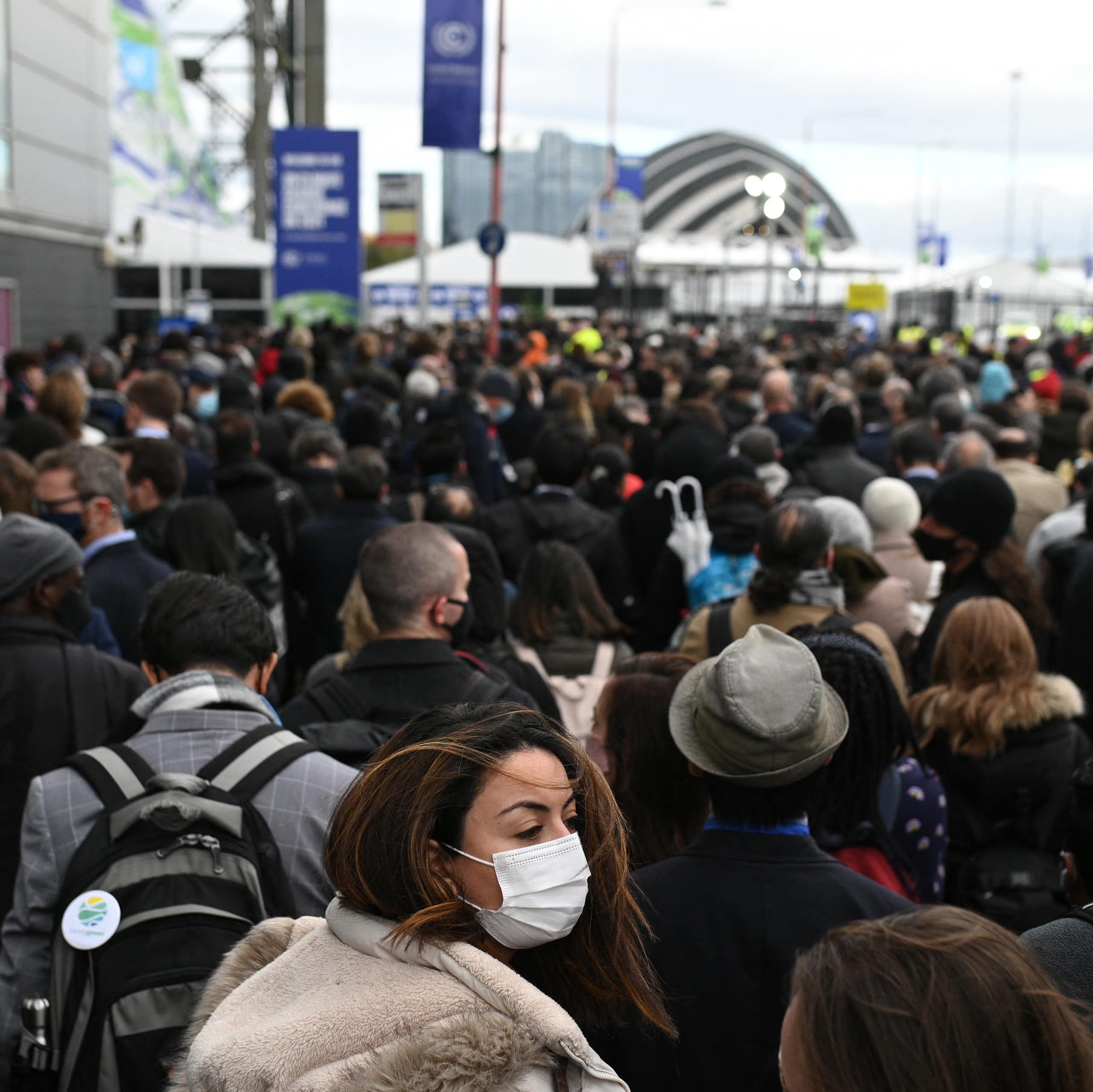 A crowd of people is seen in front of a building or event space in the distance.