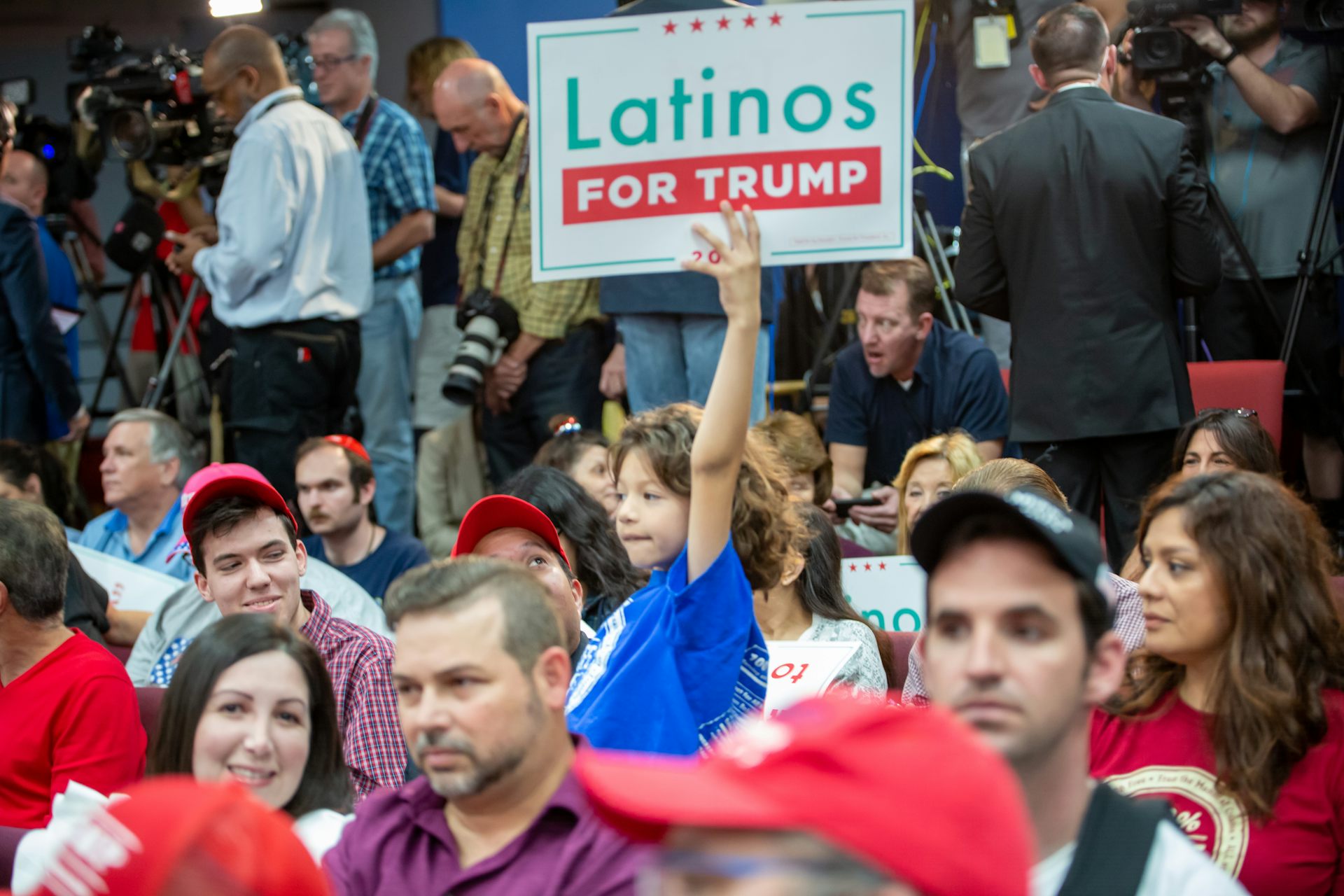 Un niño sujeta un cartel donde se lee "Latinos for Trump" 