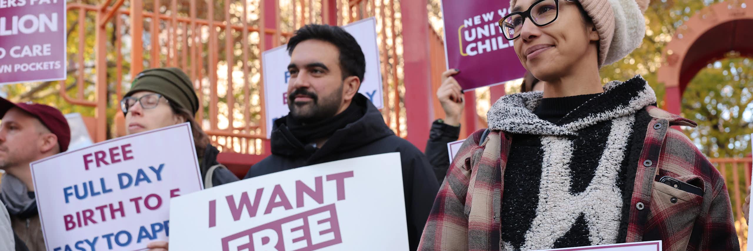 Several people hold signs supporting universal child care.