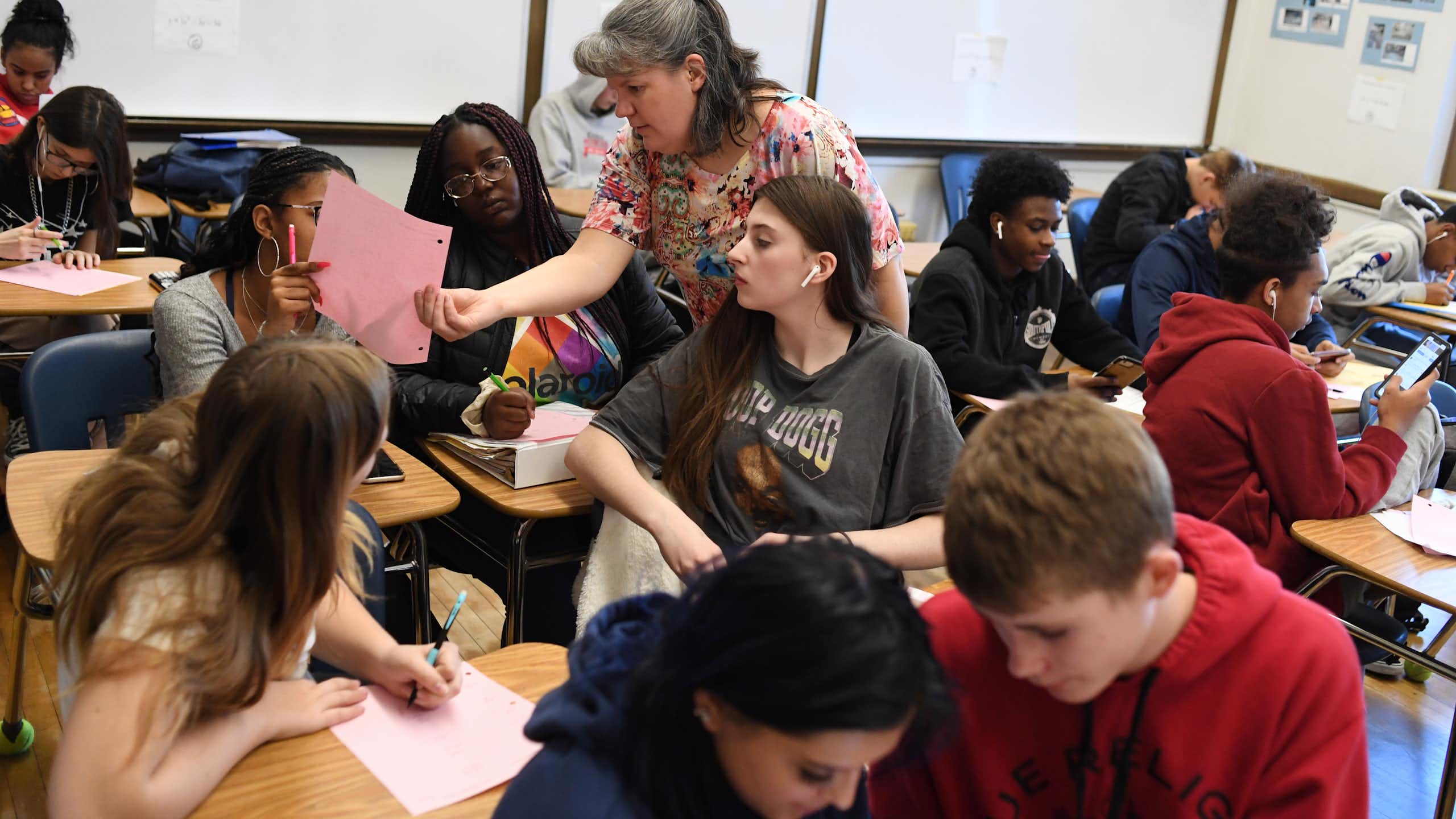 An adult stands in the middle of a busy classroom.