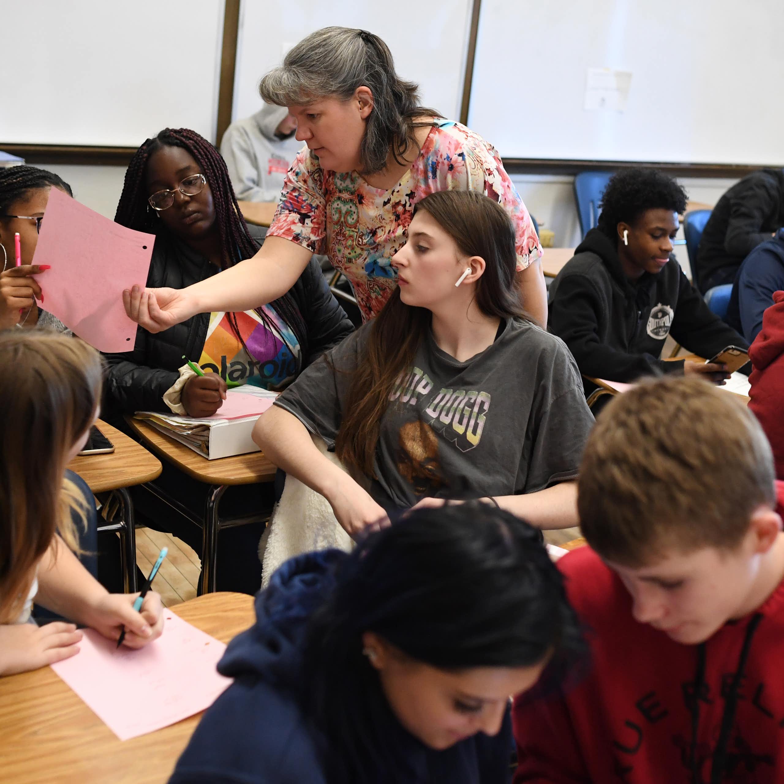 An adult stands in the middle of a busy classroom.