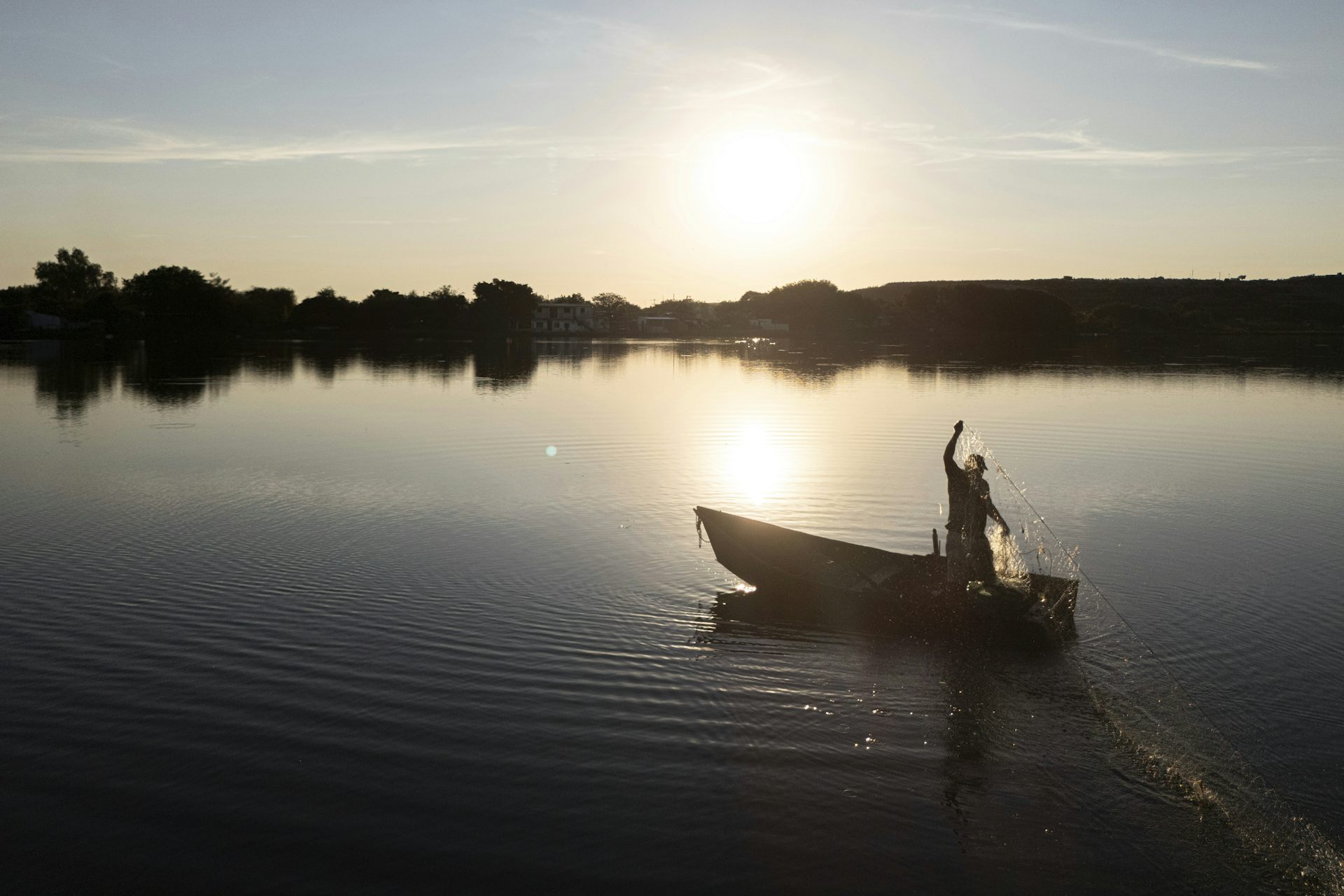 a man carrying a net standing on a boat floating on a body of water 