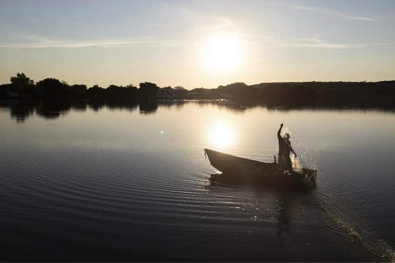 a man carrying a net standing on a boat floating on a body of water
