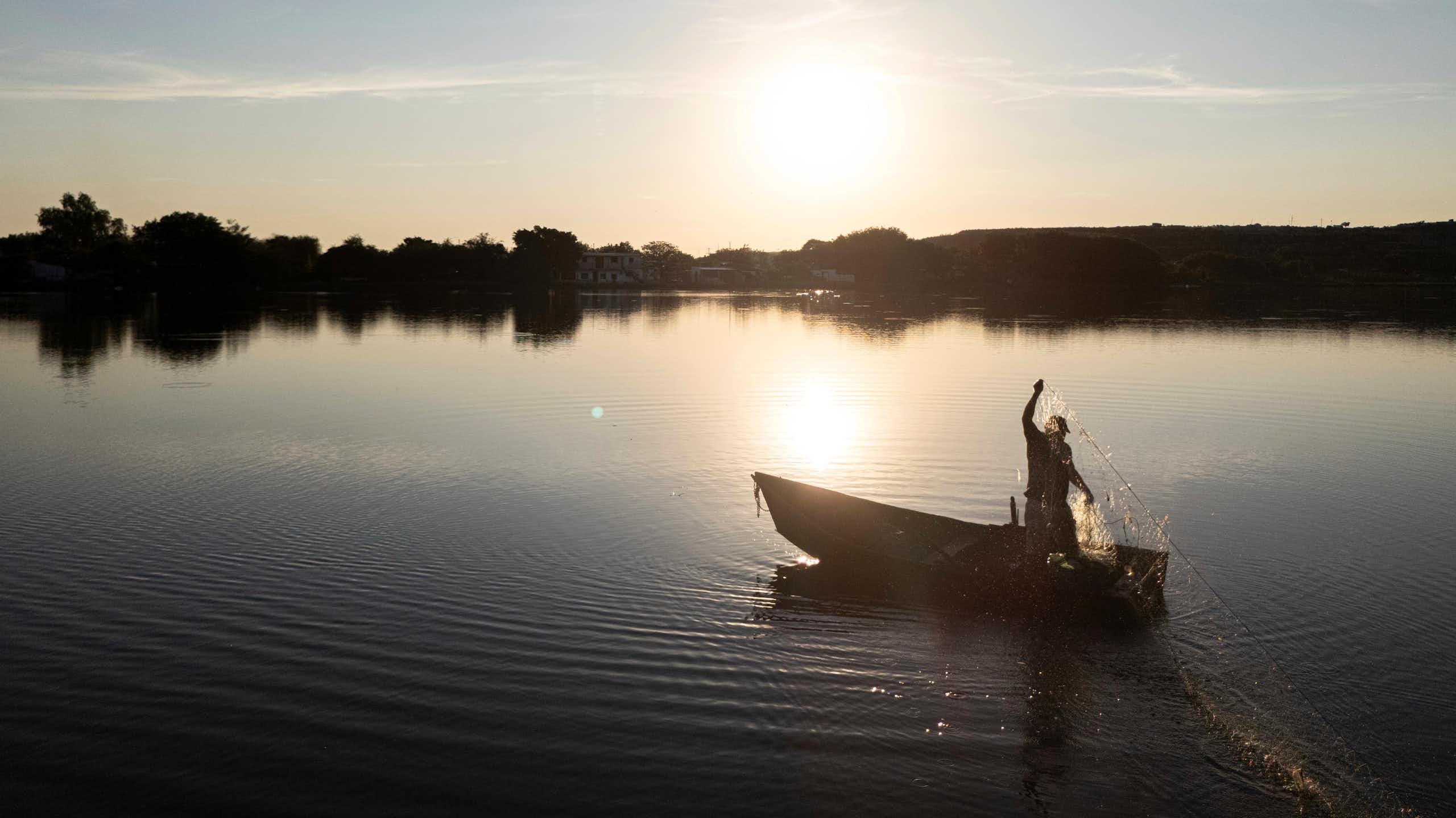 a man carrying a net standing on a boat floating on a body of water