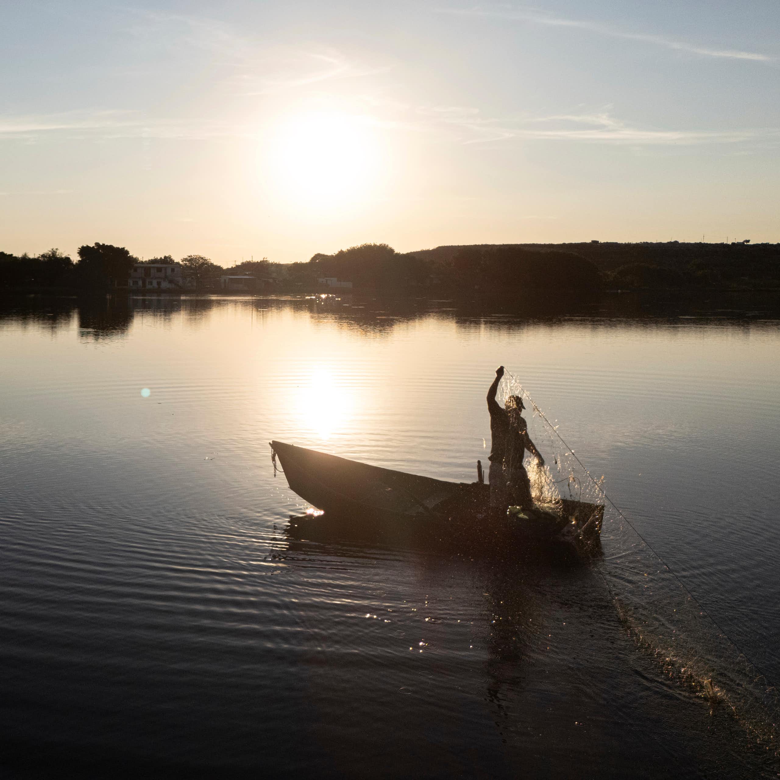 a man carrying a net standing on a boat floating on a body of water
