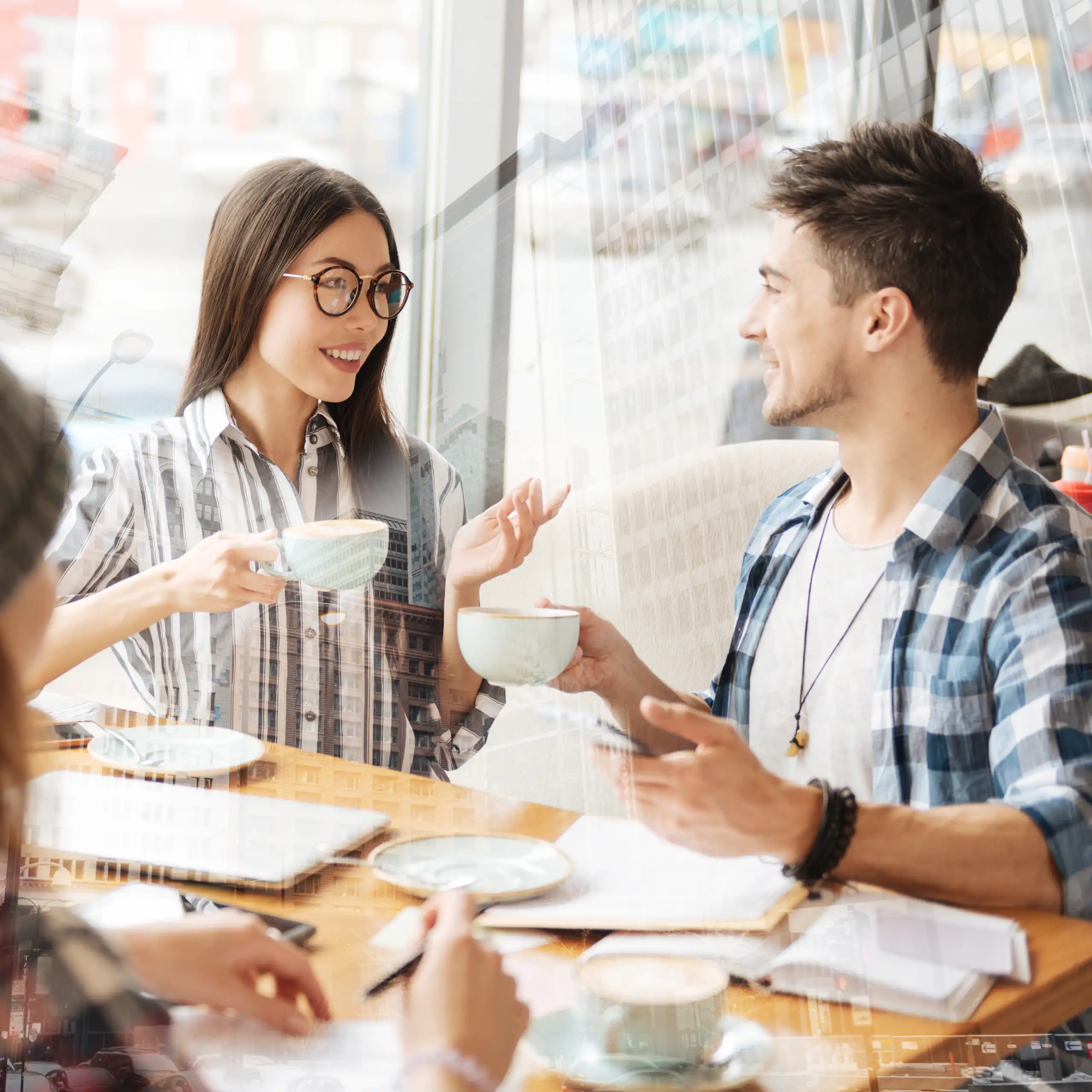 four diverse young people sit at a table at a cafe and talk