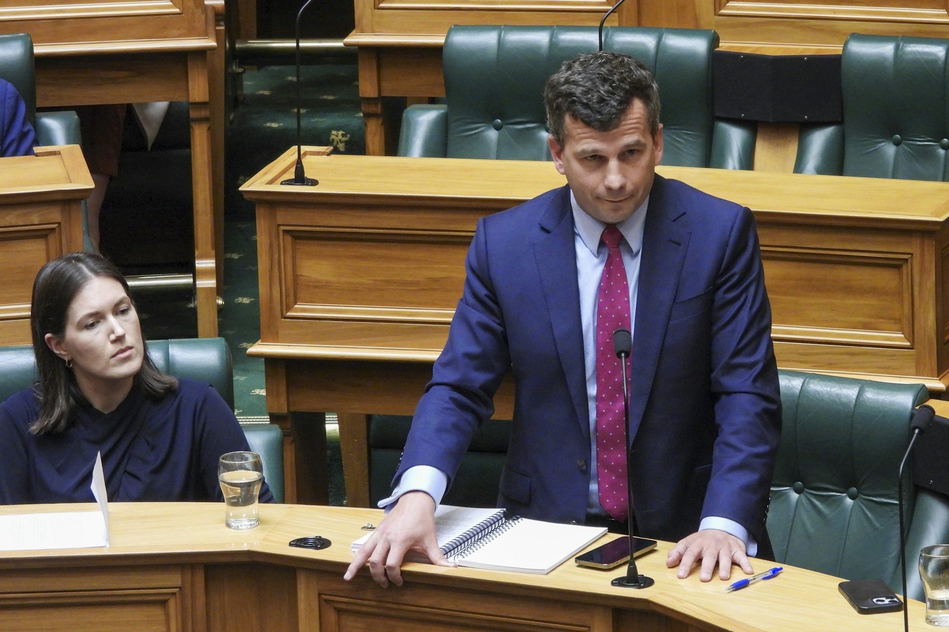 A dark-haired man stands in parliament.