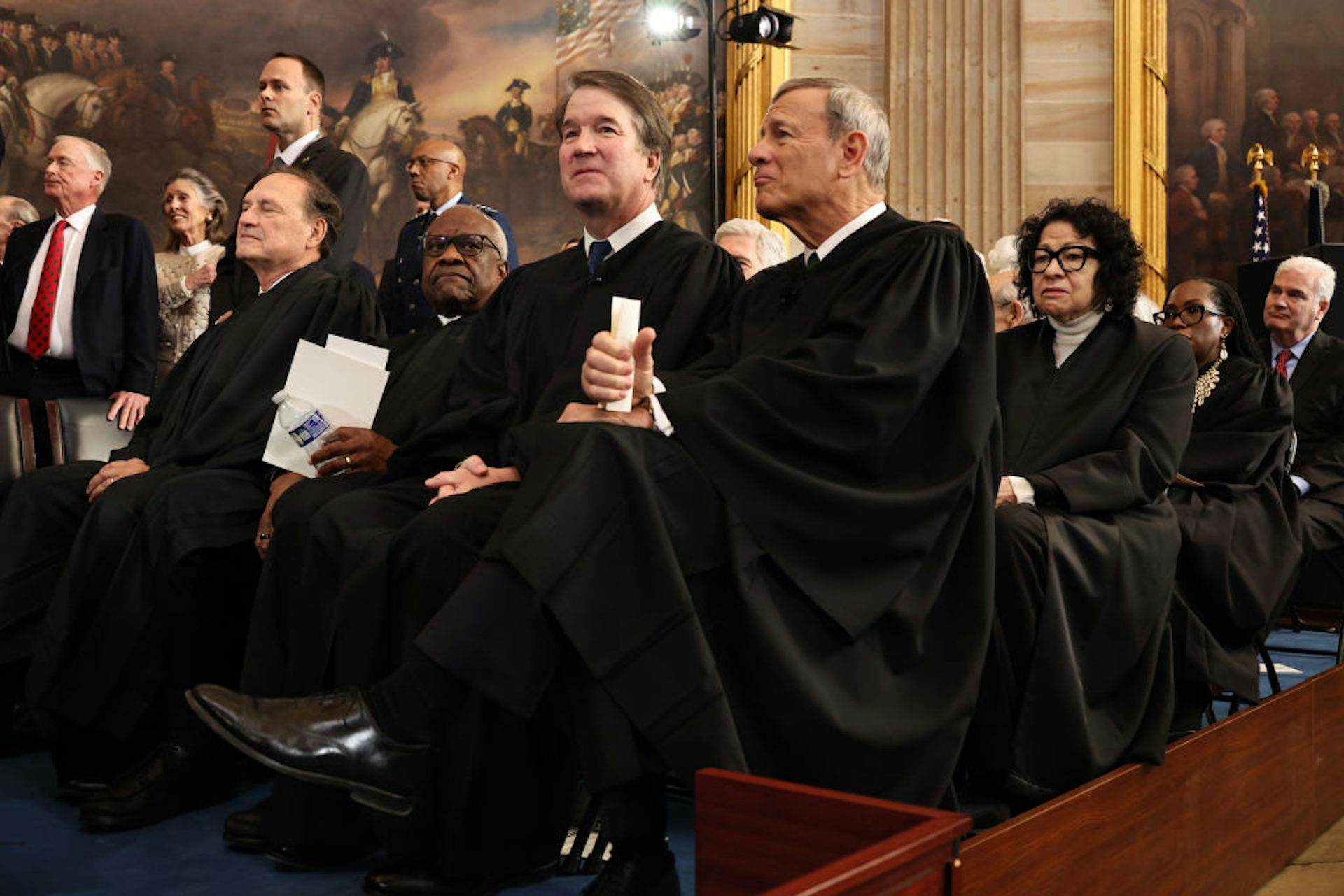 Several rows of seated men and women, many of whom are wearing long black robes.