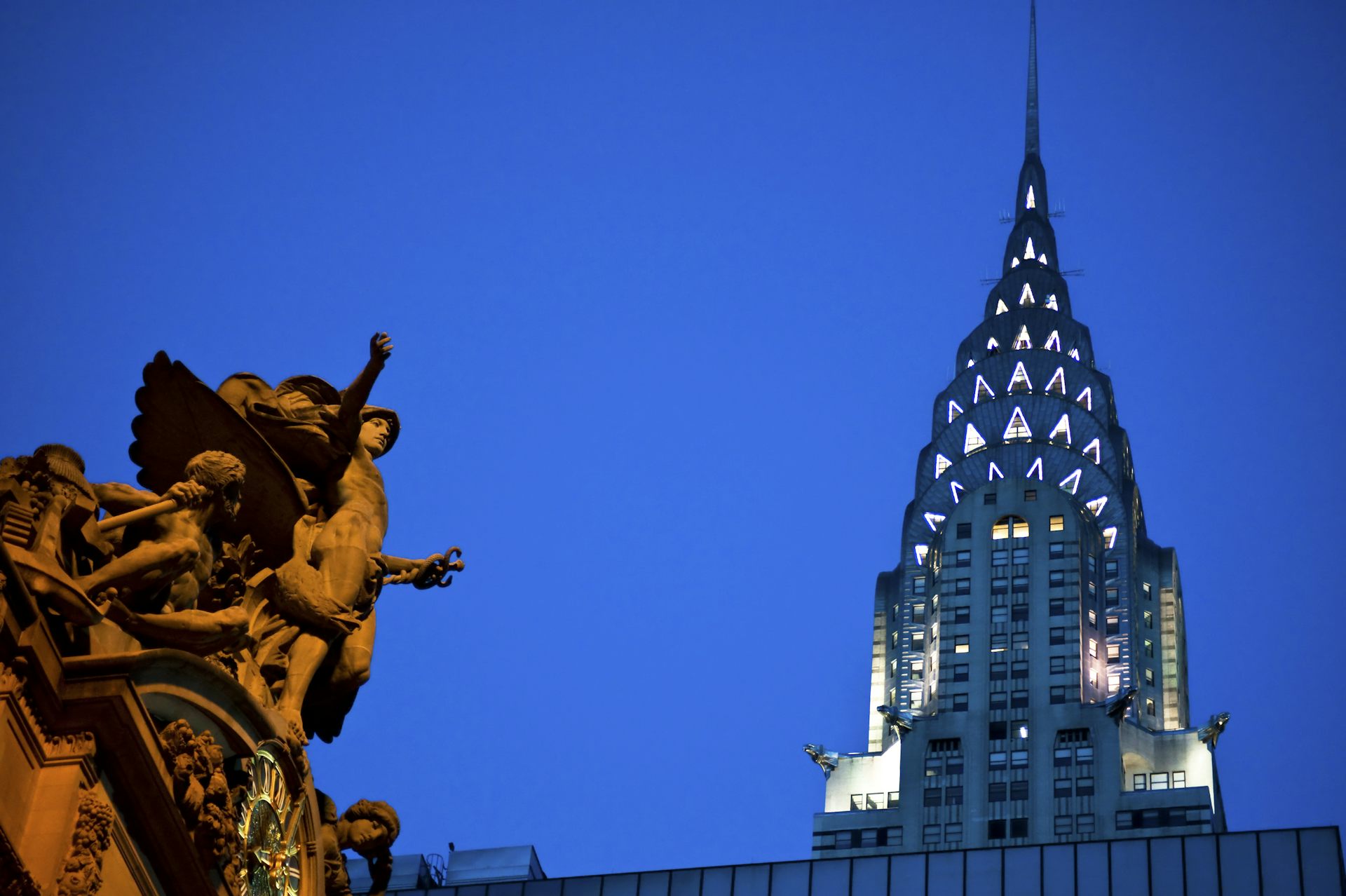 An art deco building in New York called the Chrysler Building lit up against a night sky.