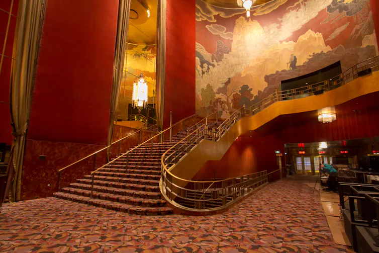 An ornate red and gold lobby with a sweeping staircase in New York's Radio City Music Hall.