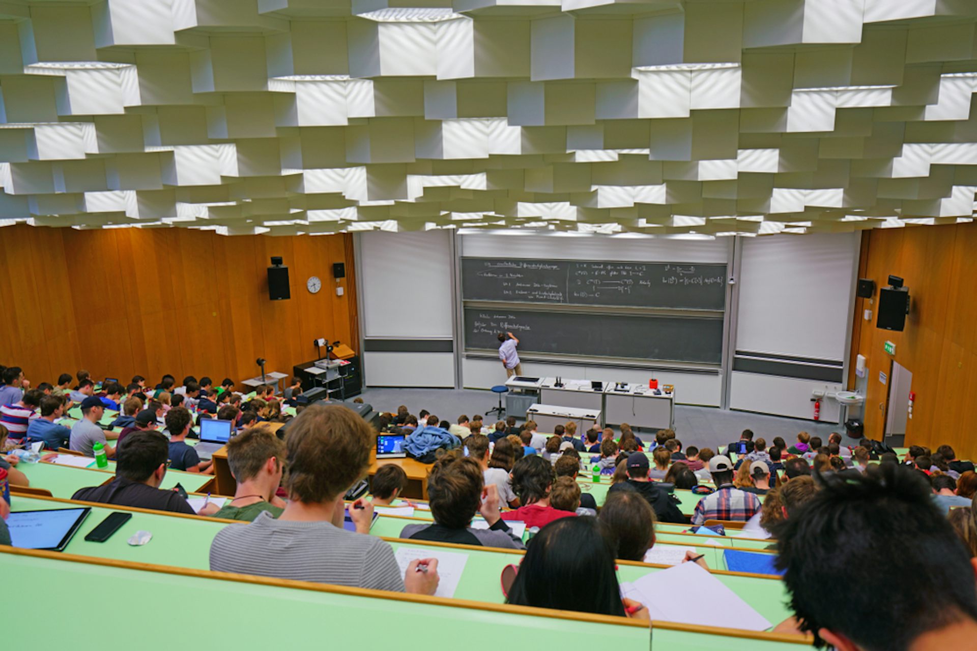 Clase en un aula grande de universidad con una pizarra al fondo