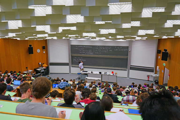 Clase en un aula grande de universidad con una pizarra al fondo