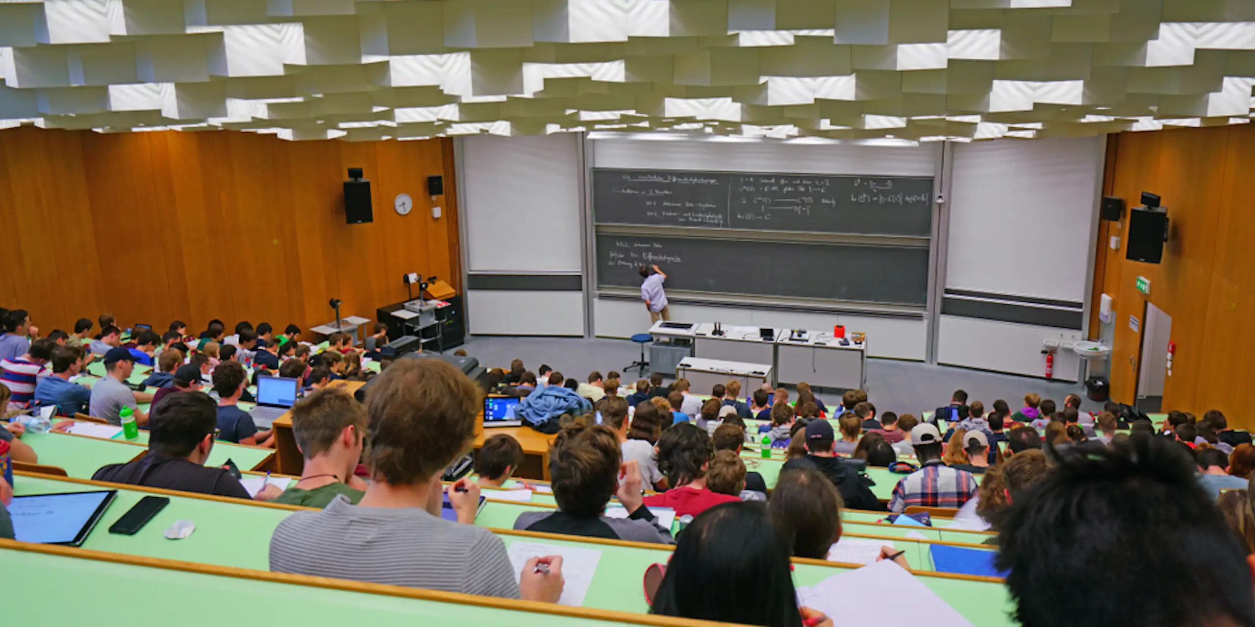Clase en un aula grande de universidad con una pizarra al fondo