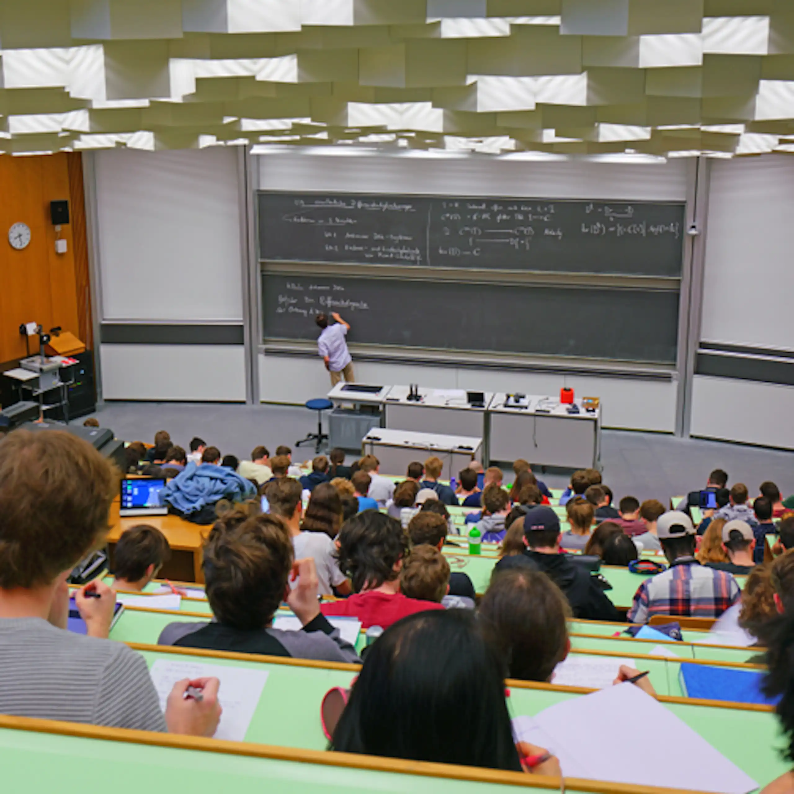 Clase en un aula grande de universidad con una pizarra al fondo