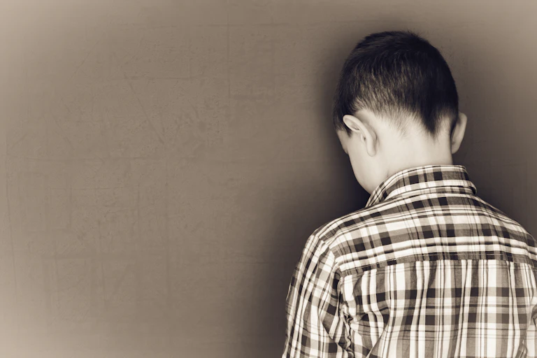 Un niño apoya la cabeza contra una pizarra