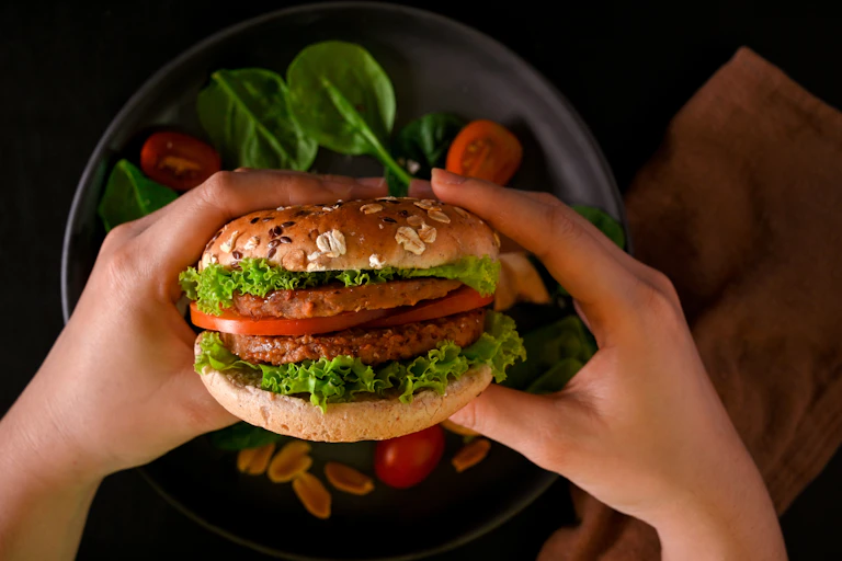 hands of person holding vegan burger