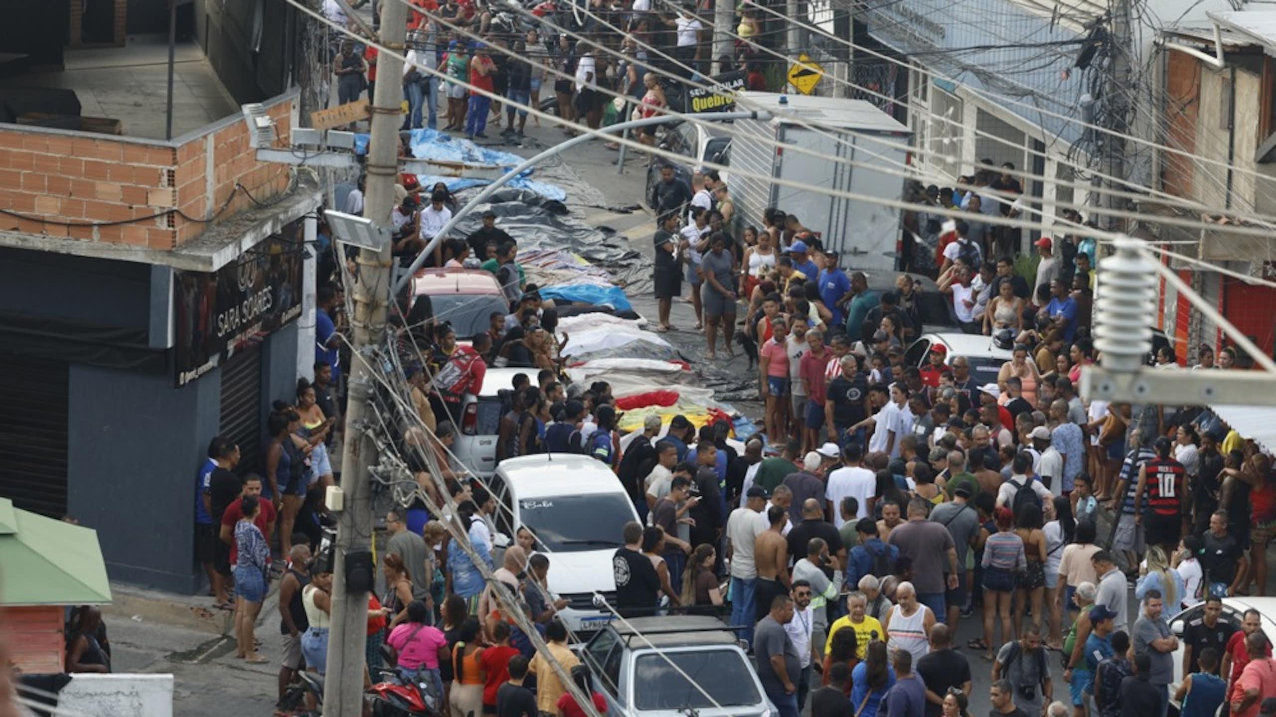 People crowd around a line of bodies in Rio de Janiero