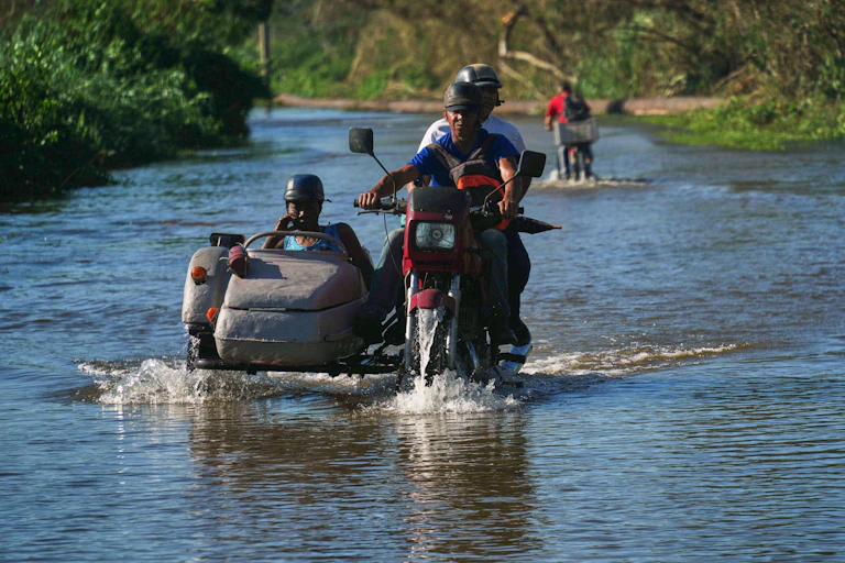 Cubans on a motorbike ride through a flooded road