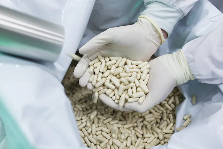 Gloved hands overflowing with manufactured tablets