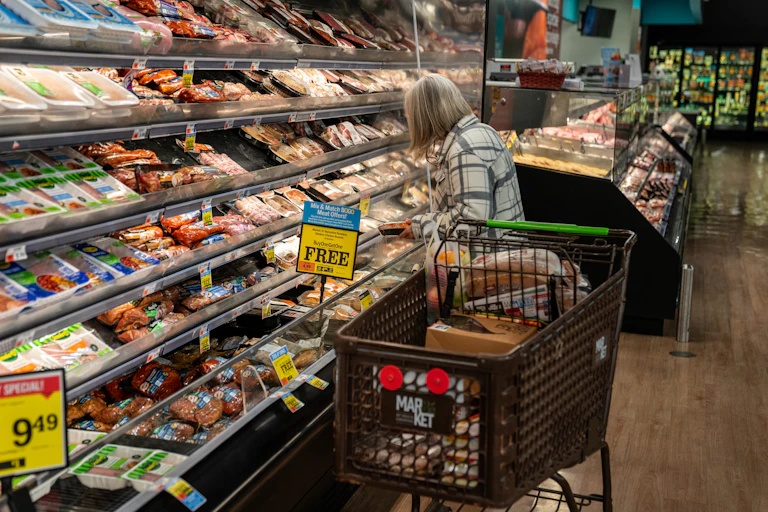 A shopper looks at a meat display at a supermarket.