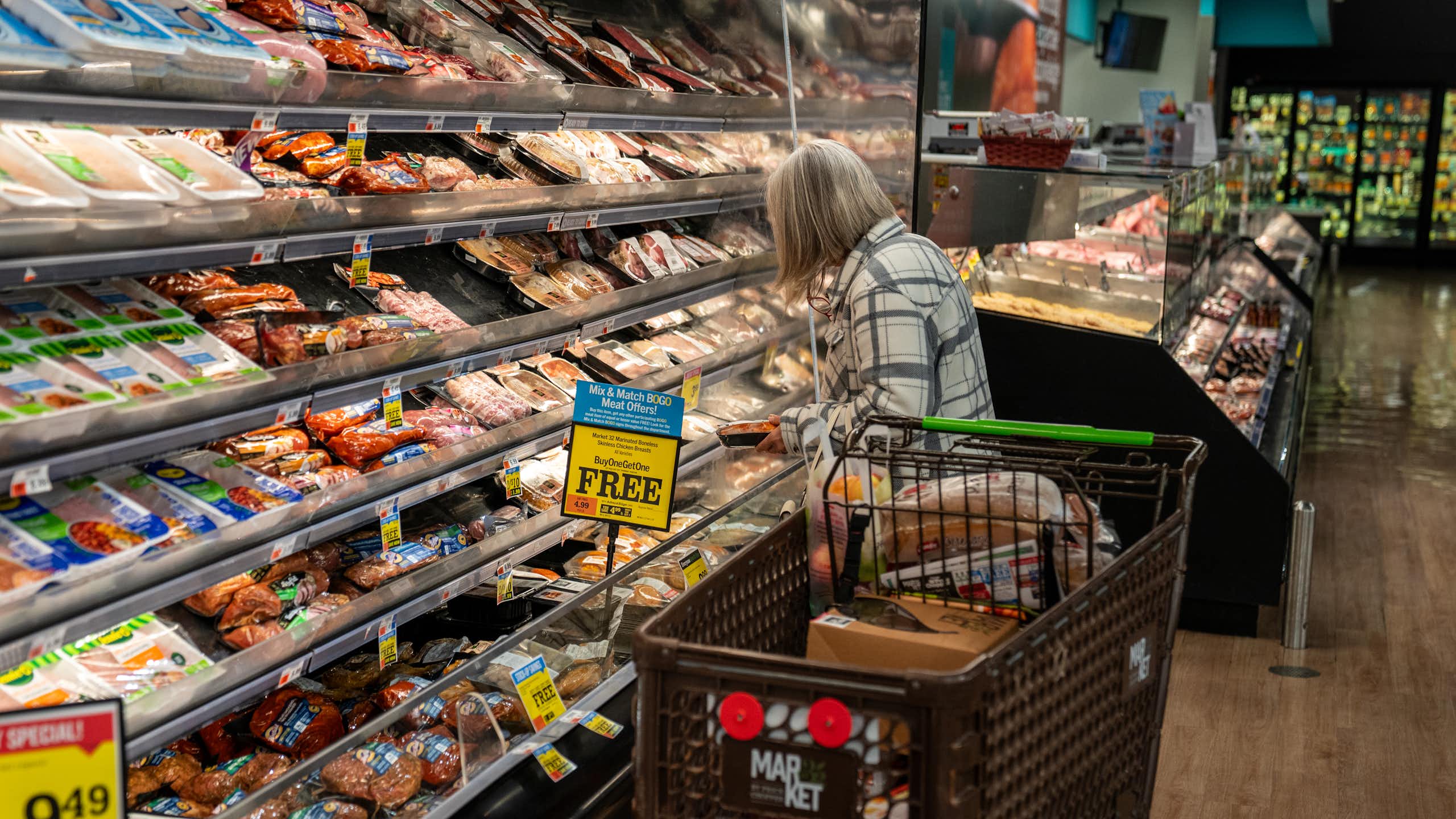 A shopper looks at a meat display at a supermarket.
