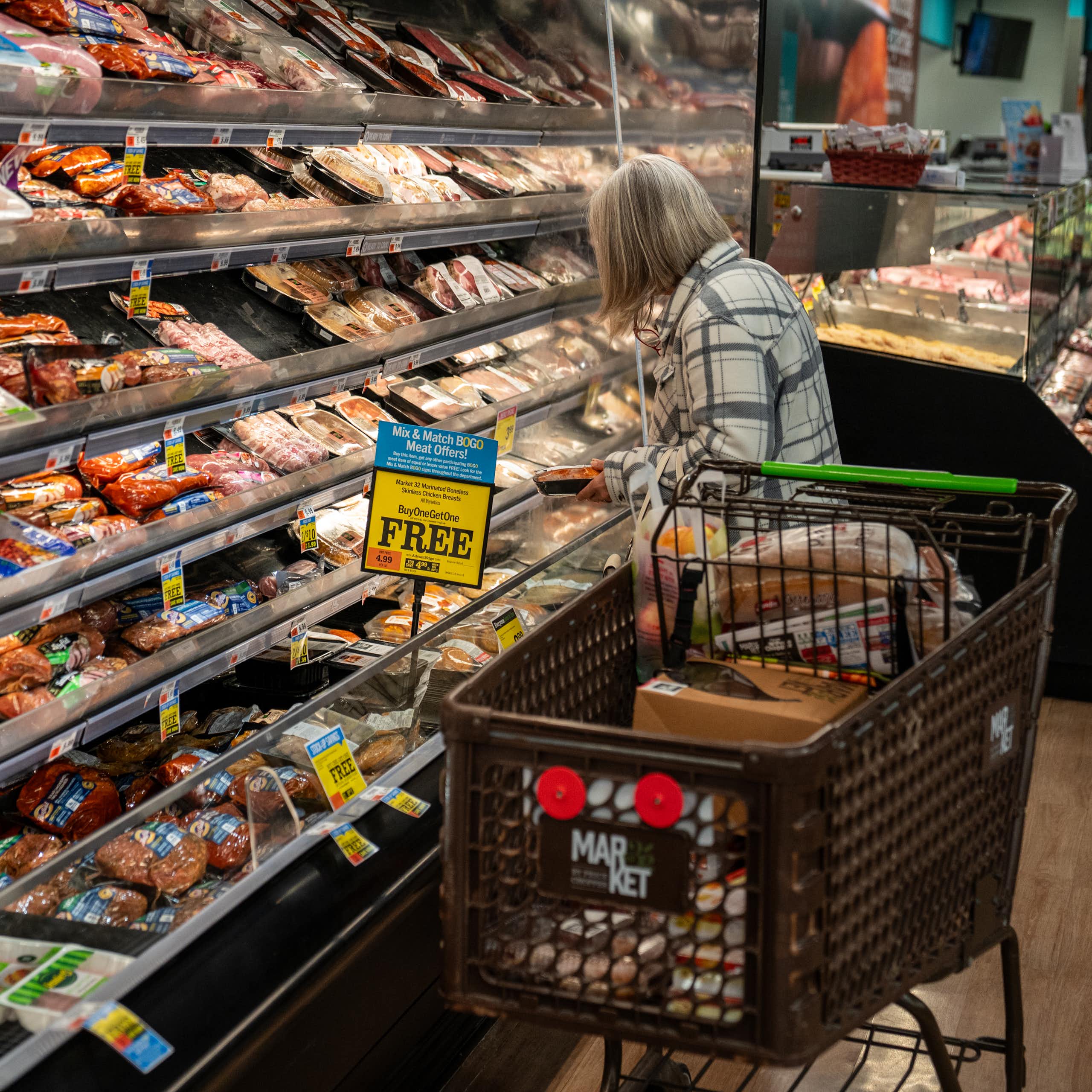 A shopper looks at a meat display at a supermarket.