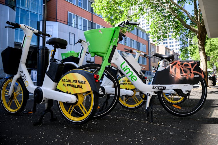 E-bikes for rent are lined up on a Sydney footpath.