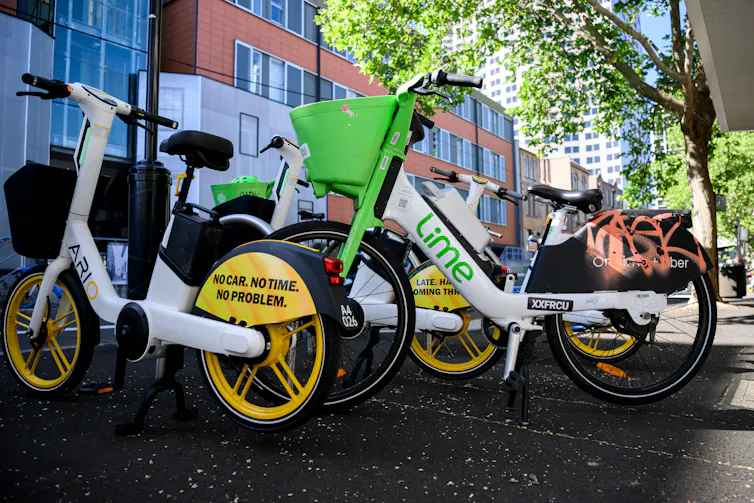 E-bikes for rent are lined up on a Sydney footpath.