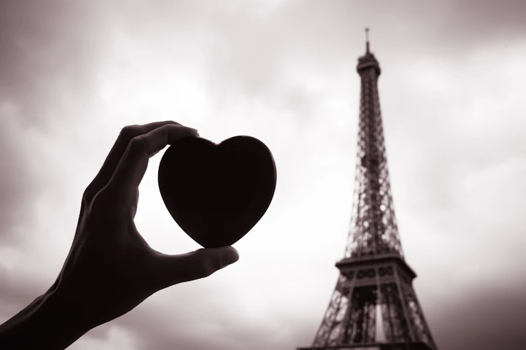 Une main tenant un coeur devant la Tour Eiffel.