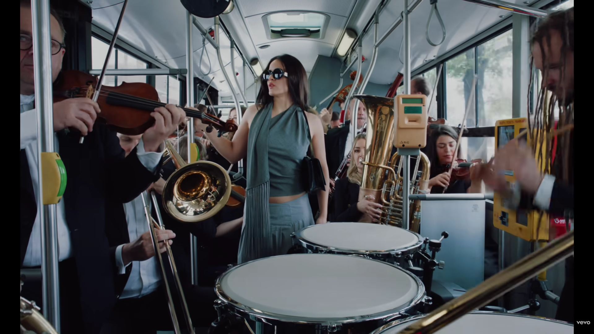 Una mujer en un autobús rodeada de músicos.