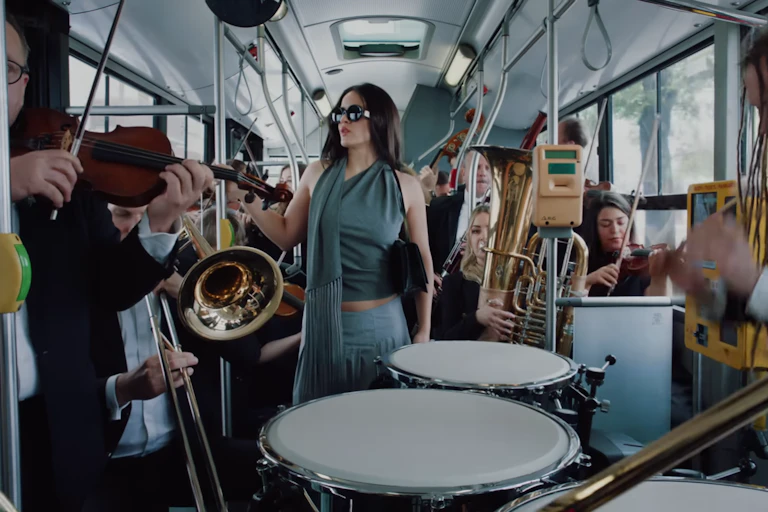 Una mujer en un autobús rodeada de músicos.