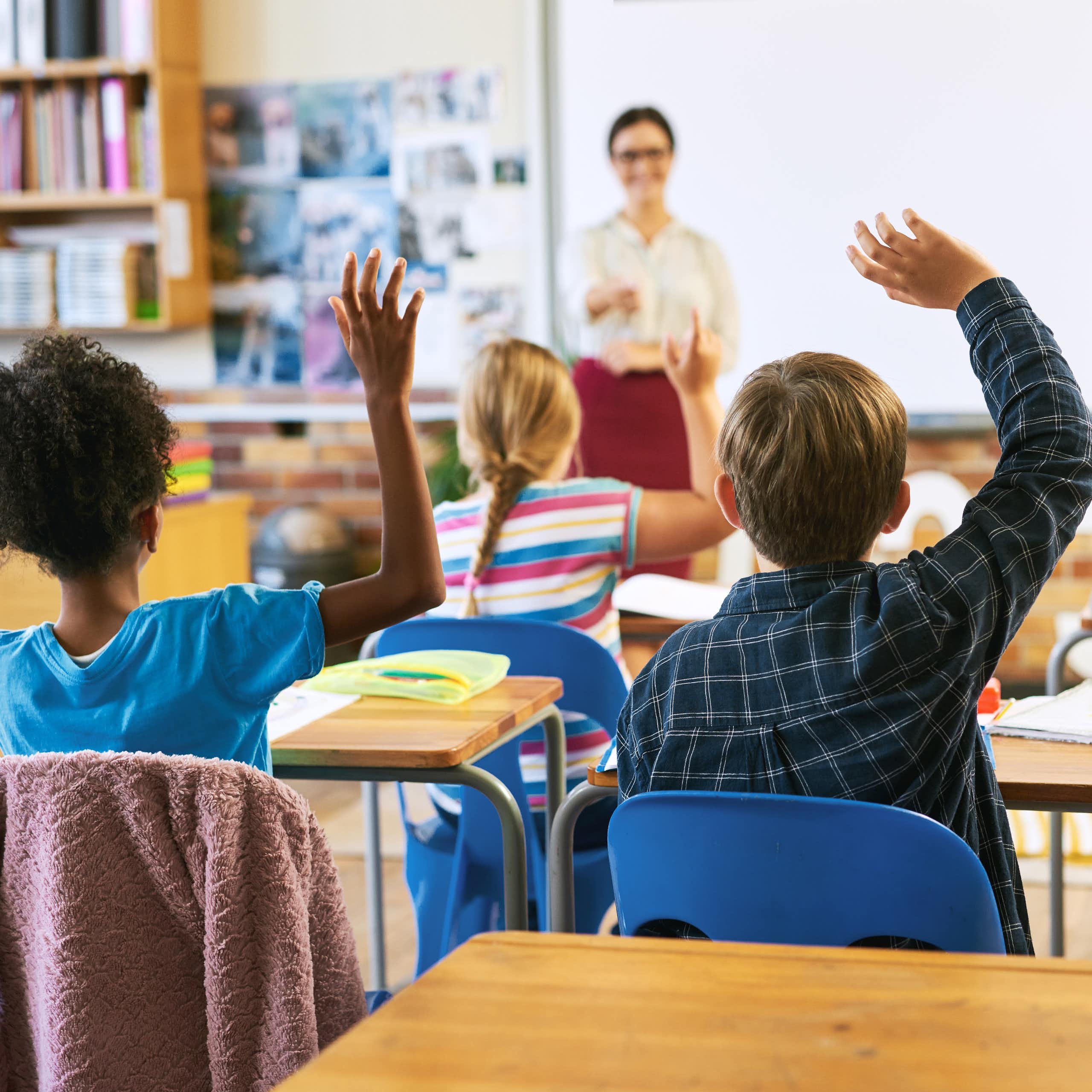 Children raising hands in class
