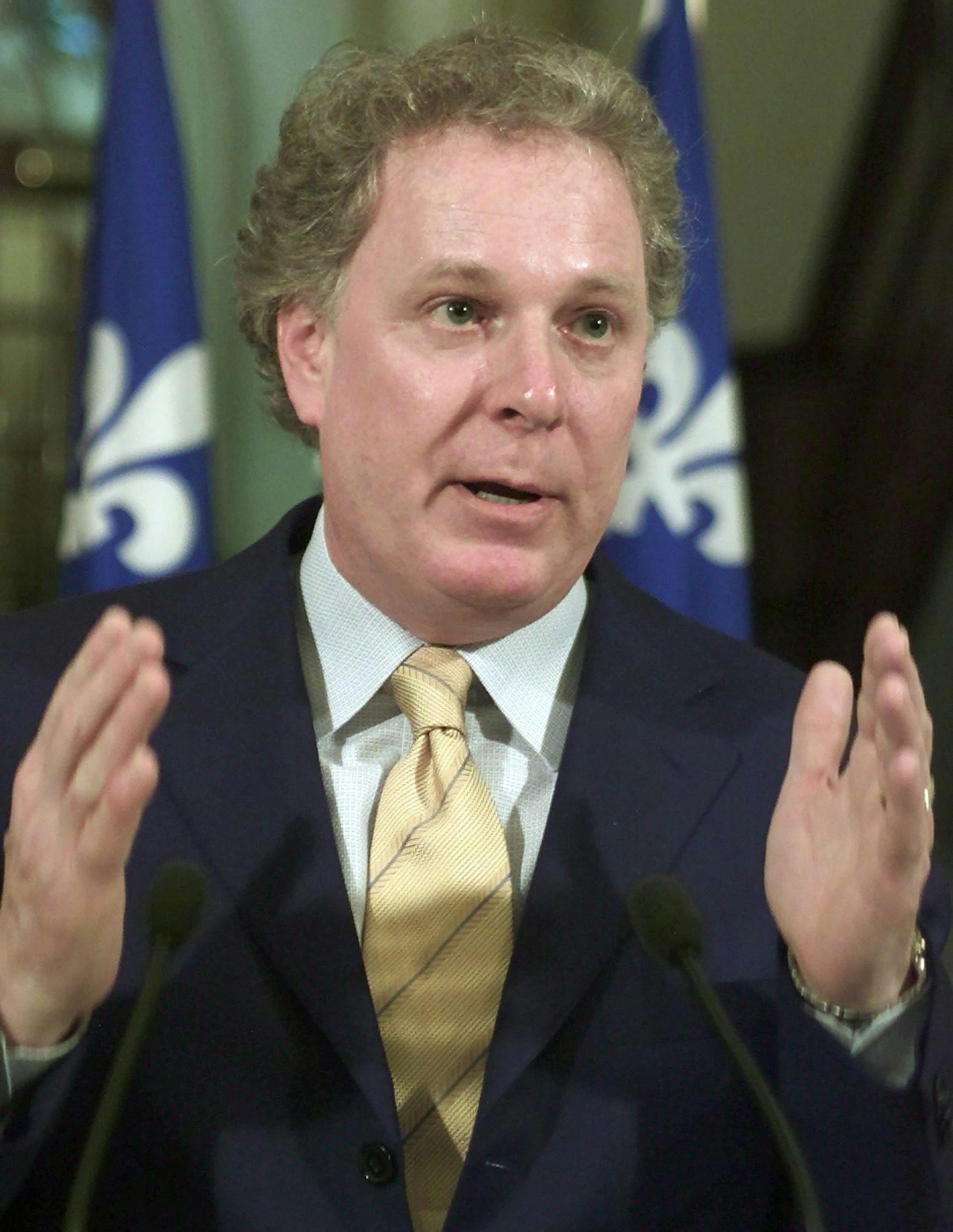 A man in suit and tie gestures with his hands.