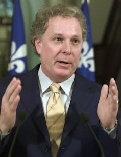 Un hombre con traje y corbata hace gestos con las manos.