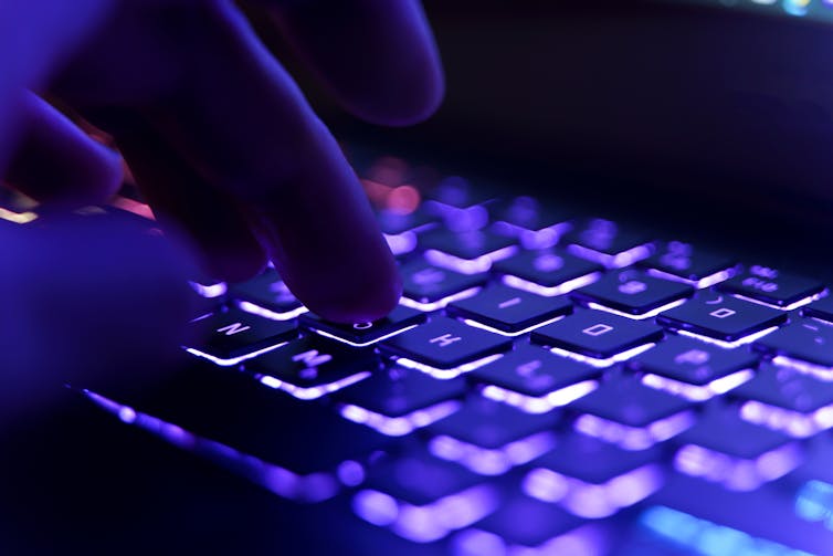 Forensic linguistics: how darkish internet criminals give themselves away with their language 1 Hand typing on neon lit keyboard