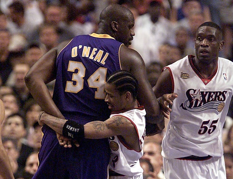 Allen Iverson’s 2001 Sixers embodied Philly’s brash, gritty soul − and altered basketball tradition perpetually 3 Basketball player in white uniform and sweatband that says 'The Answer' wraps arms around much taller player in purple and yellow uniform