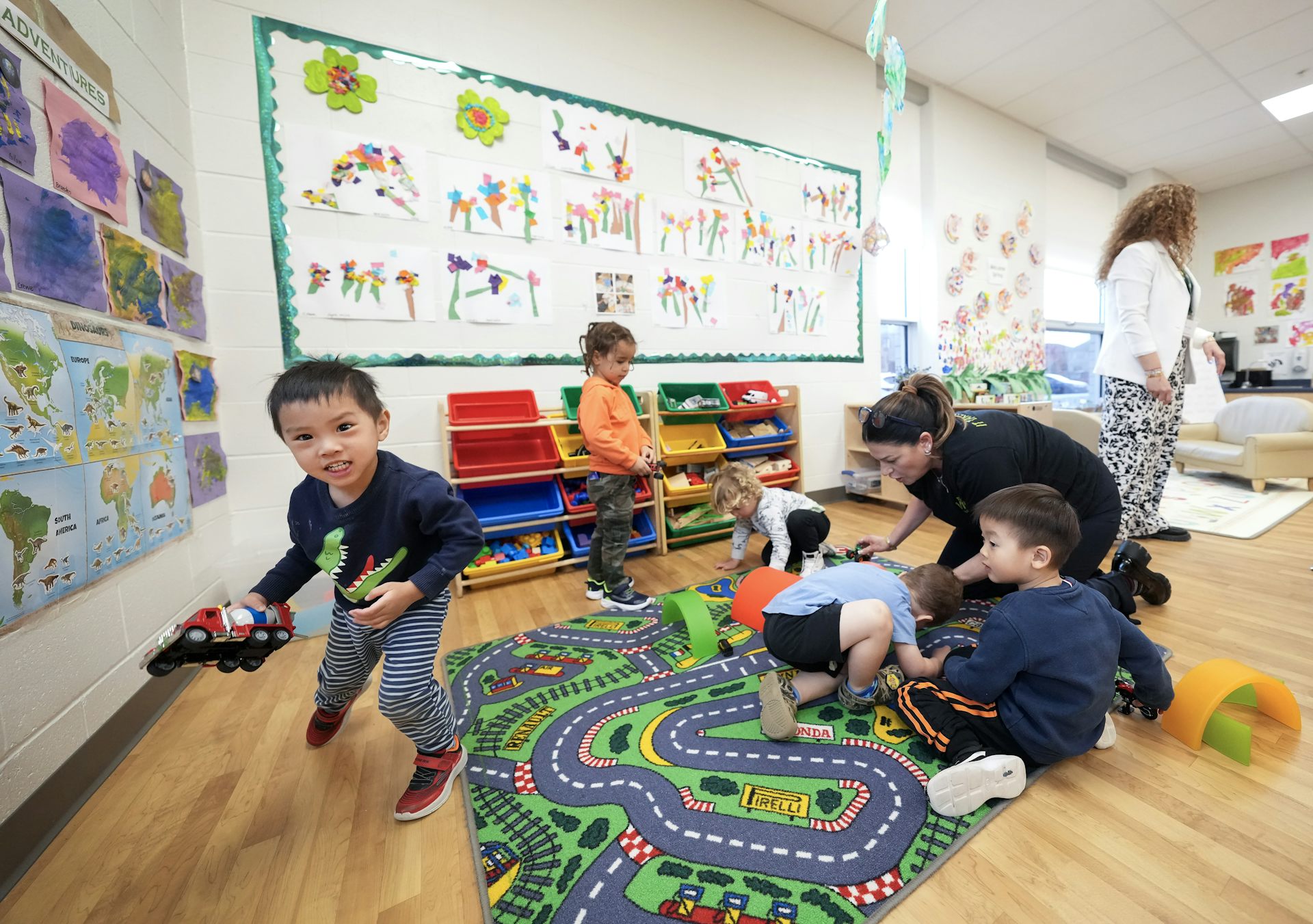 Children playing in a child care centre, while a child care worker accompanies them.