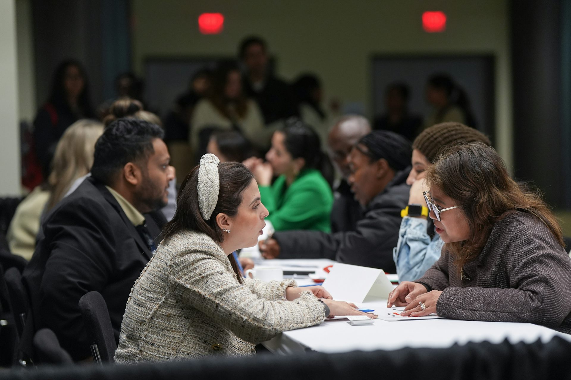 People seen in discussion at tables at a public event.
