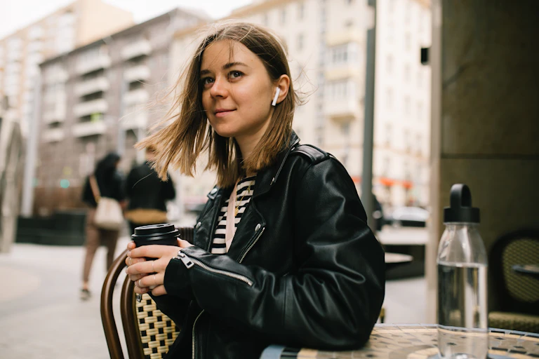 Woman listening to headphones and holding a coffee