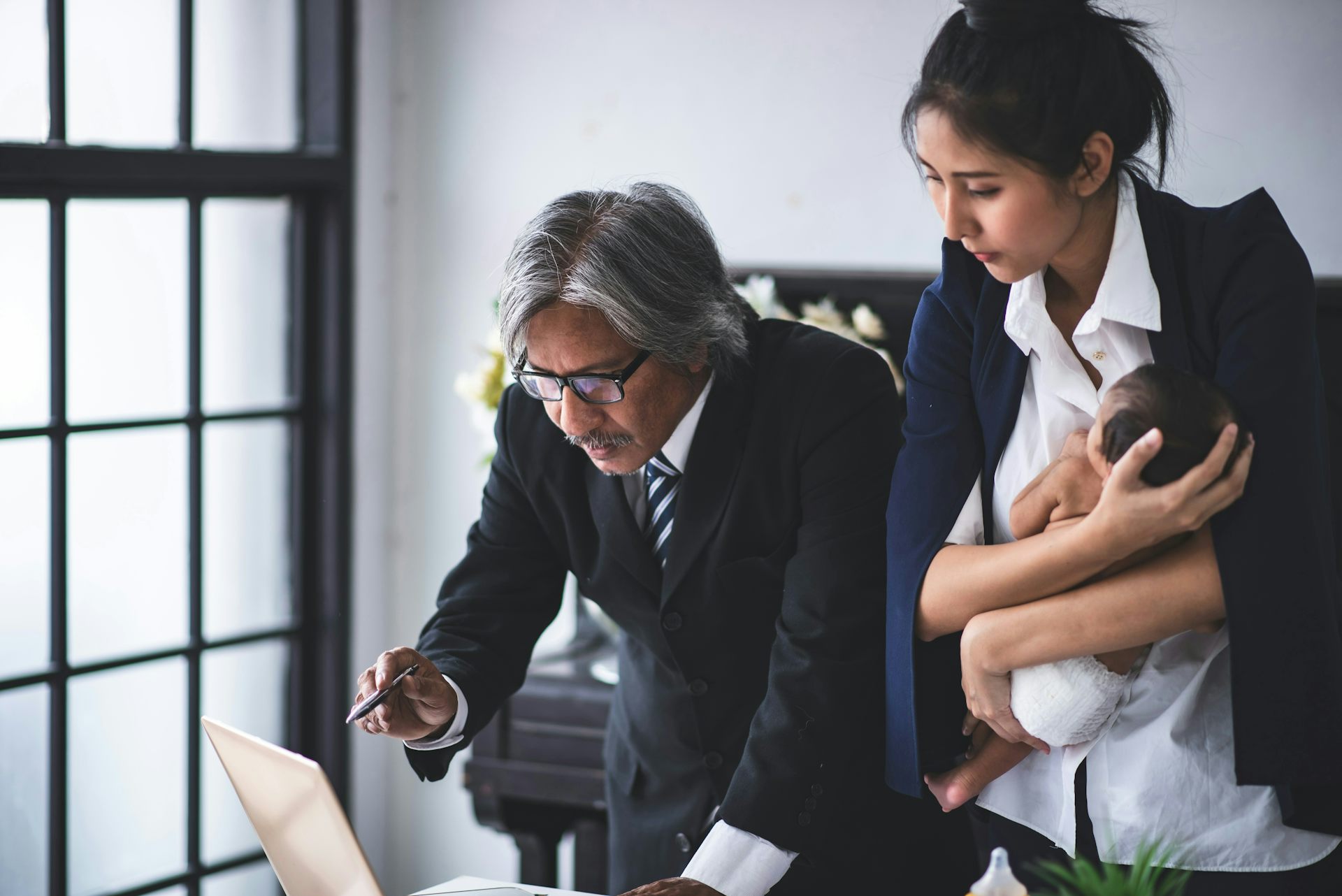 Un hombre y una mujer sosteniendo un bebé hablan mientras revisan documentos