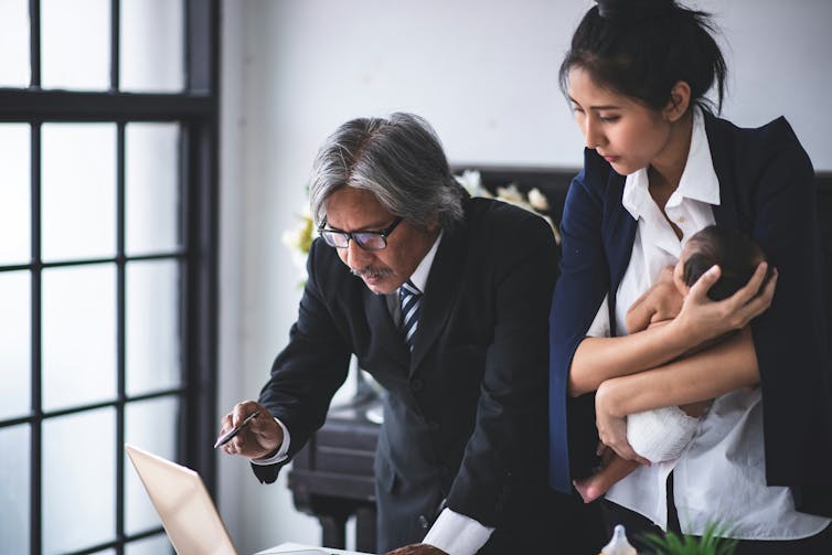 Un hombre y una mujer sosteniendo un bebé hablan mientras revisan documentos