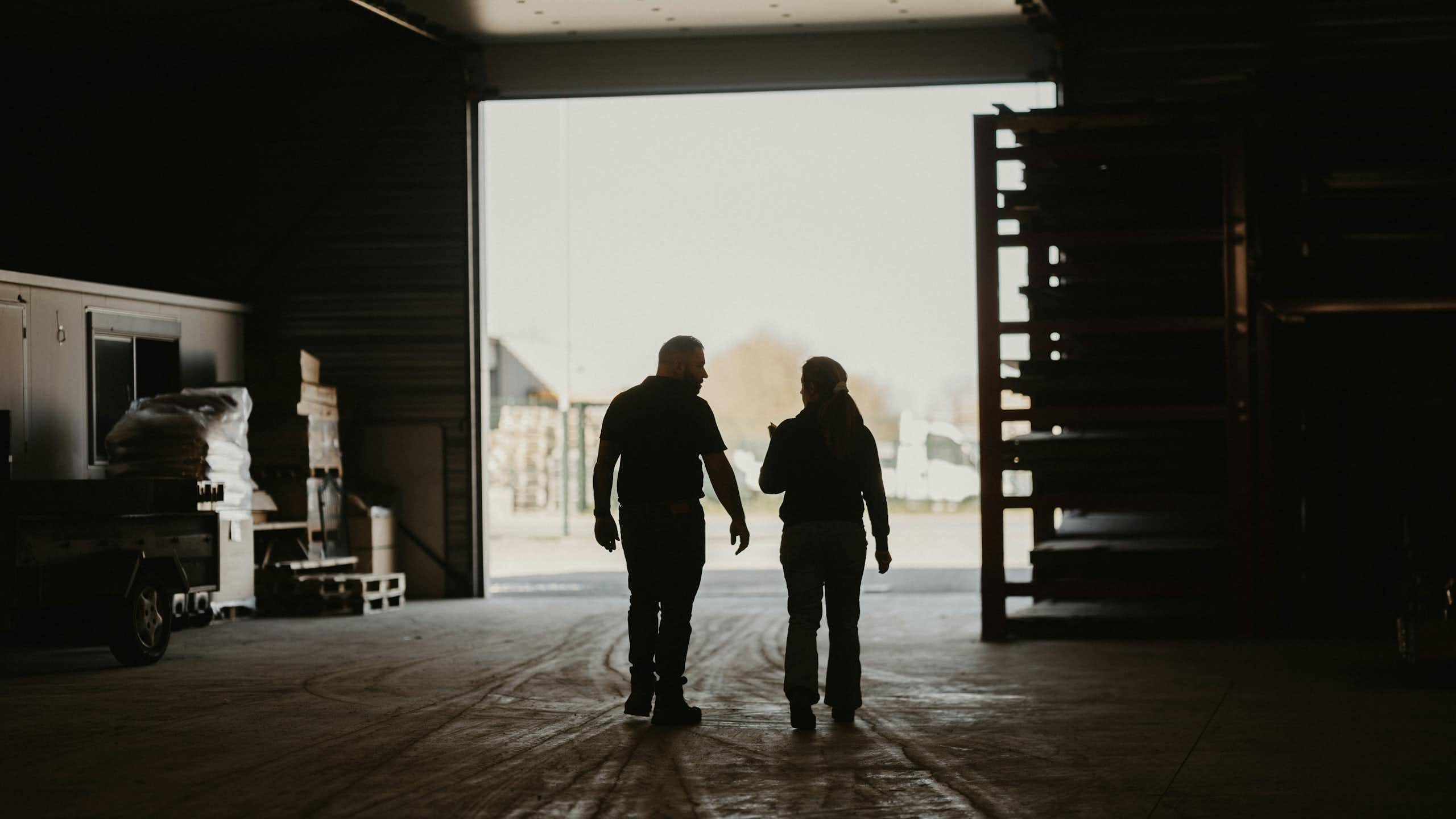 A man and a woman walk through a warehouse together