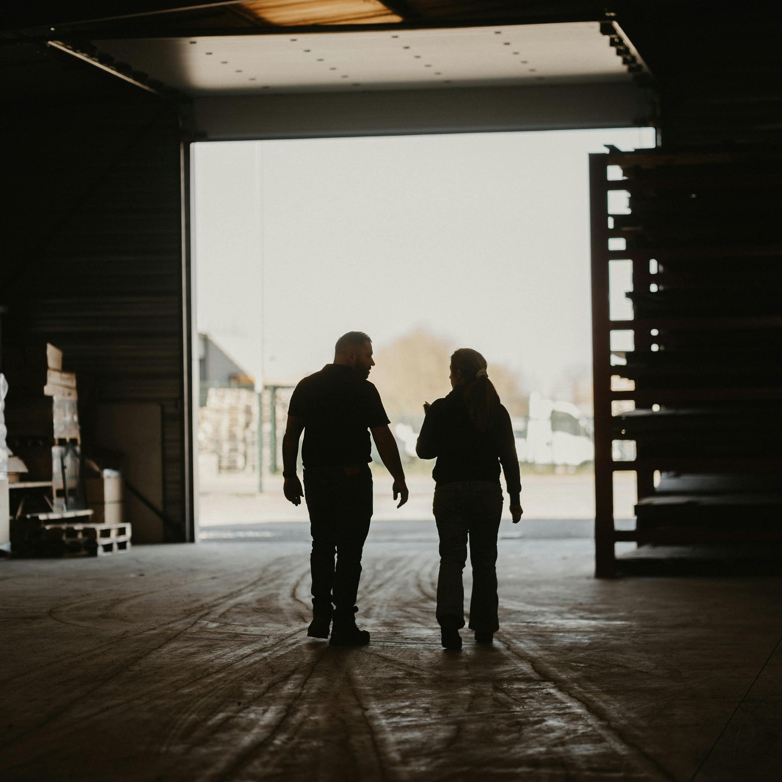A man and a woman walk through a warehouse together