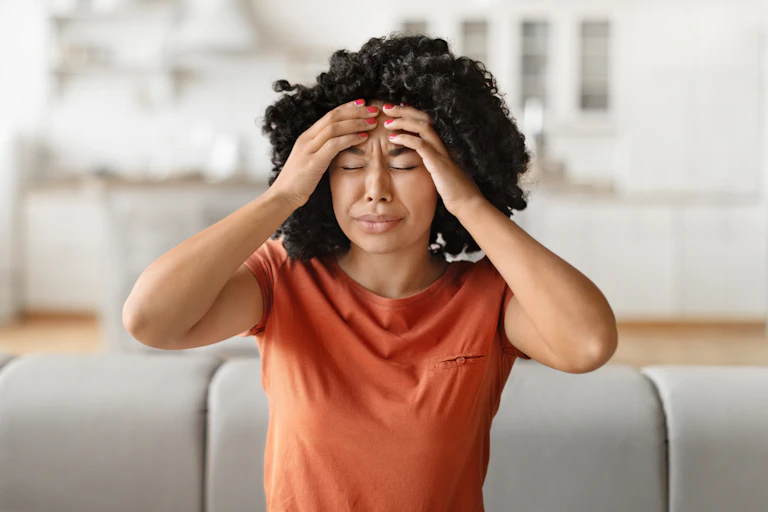 Woman experiencing severe headache holds both hands to her forehead