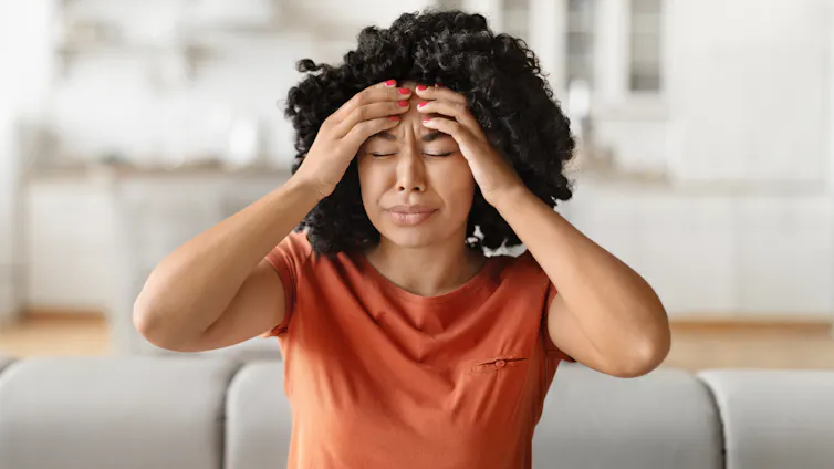 Woman experiencing severe headache holds both hands to her forehead