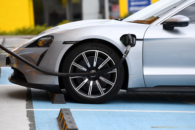 A charging cable attached to a silver car.
