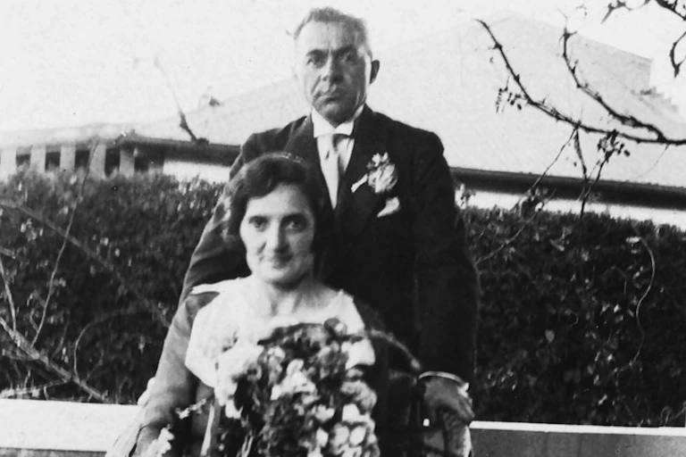 Black and white photo of a seated woman holding a bouquet of flowers and a man standing behind her